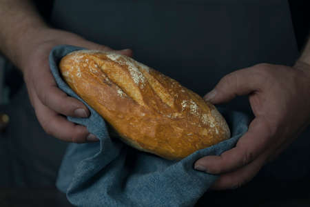 Baker holding organic bread bake bread rolls in hands - rural bakery, moody still life.の写真素材