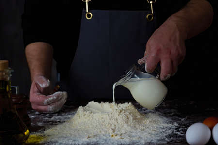 Man puts Milk in flour.Preparation of dough for dumplings. For making dough for bread.の写真素材