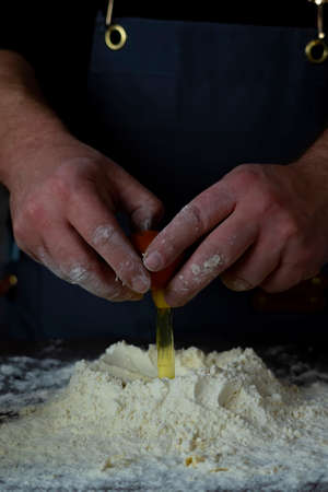 Man puts egg yolk in flour.Preparation of dough for dumplings. For making doughの写真素材