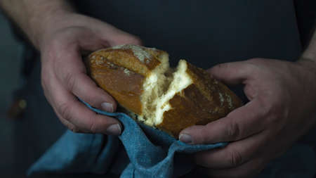Baker holding organic bread bake bread rolls divided in half in hands - rural bakery, moody still life.の写真素材
