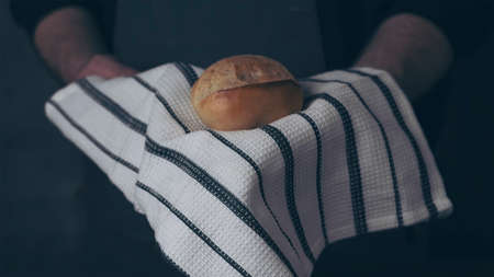 Baker holding organic bread bake bread rolls in hands - rural bakery, moody still life.の写真素材