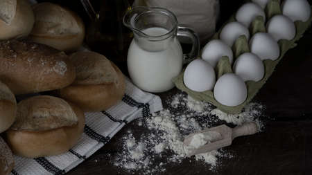 Bread rolls,  Flour, milk and eggs on wood table.Breakfast or cooking concept.の写真素材
