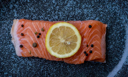 Row Salmon fish fillet uncooked with different spices and lemon slice served on plate.の写真素材