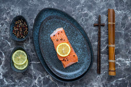Row Salmon fish fillet uncooked with different spices and lemon slice served on plate.の写真素材