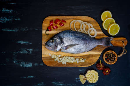 Mahi-mahi or widely called dorado fish row, top view.on wood cutting board and a wooden black table.の写真素材
