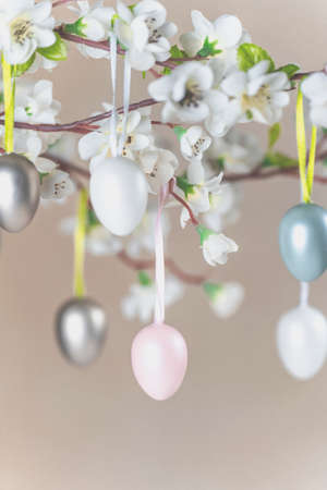 Colored Easter eggs hanging on branch with white flowers