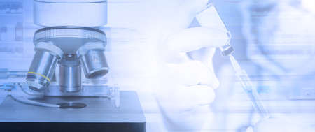 Banner of Science Microscope in laboratory and Doctor wearing surgical mask and surgical gloves holding a needle for injection. Medical health  research and development concept.の写真素材