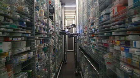 Modern pharmacy storage room and a robot hand is arranging and storing out drugs in a pharmacy.のeditorial素材