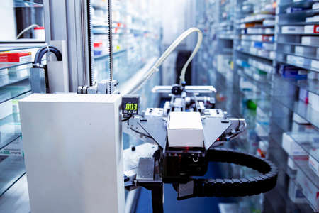 Modern pharmacy storage room and a robot hand is arranging and storing out drugs in a pharmacy.