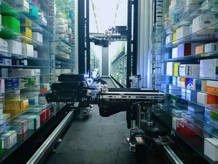Modern pharmacy storage room and a robot hand is arranging and storing out drugs in a pharmacy.のeditorial素材
