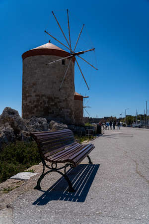 Rhodes Windmills in Mandraki Harbor in focus and Seaside chair at sunset .の写真素材