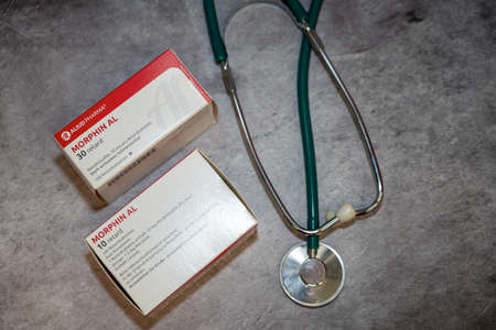 Drug box of  Morphine,pain medication of the opiate.On a table and in the background different medical books.のeditorial素材