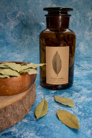Dray Laurus nobilis Leafs in a wooden plate and dark botanic glass bottle.
