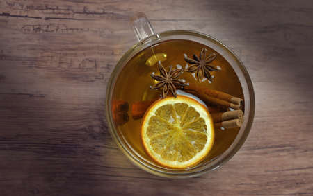 Cup tea with orange and cinnamon and anise on wooden background