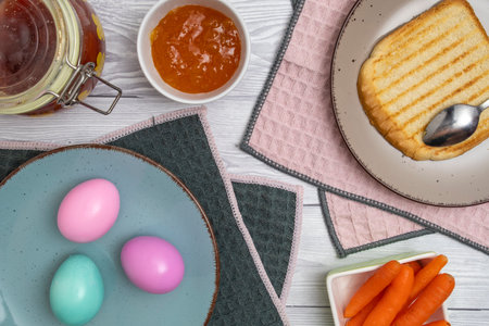 Easter egg in plate on a breakfast table with jam and pink white tulips.
