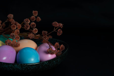 Flowers and pastel colored Easter eggs in a dark granite plate against Black background.の写真素材