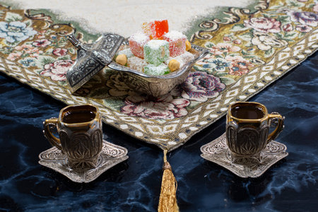 Lokum,Turkish delight a Turkish soft sweet with silver Turkish coffee. Cups. on dark background .
