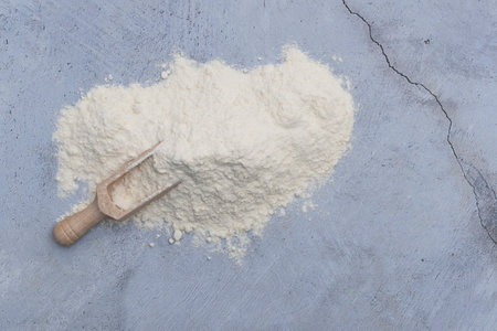 White flour powder with wooden spoon on rustic stone table.の写真素材