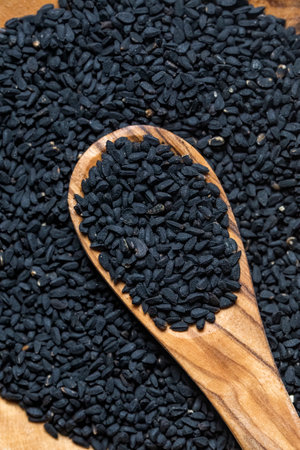Nigella sativa seeds, close up photography, with a wooden spoon, selective focus.
