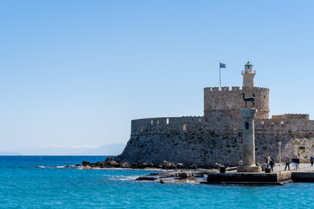 Saint Nicholas Fortress in Mandraki Harbor in focus and Seaside chair at day time.のeditorial素材