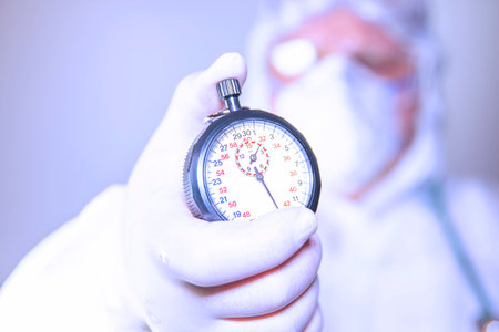 A Doctor wearing surgical mask and surgical gloves holding a stopwatch for rapid action to resist...