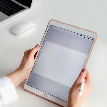 Female hands holding a tablet computer with a blank screen and a mouseの写真素材