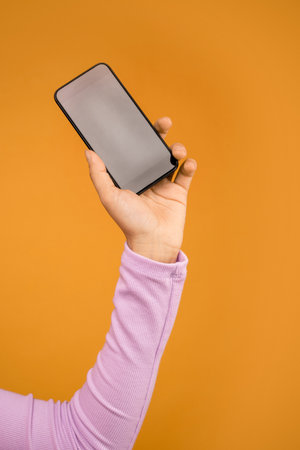 cropped view of woman holding smartphone with blank screen isolated on orange