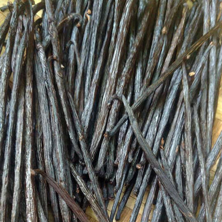 Dried black vanilla sticks on a wooden background. Close-up.
