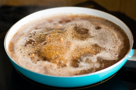 Chicken broth in frying pan at stoveの写真素材