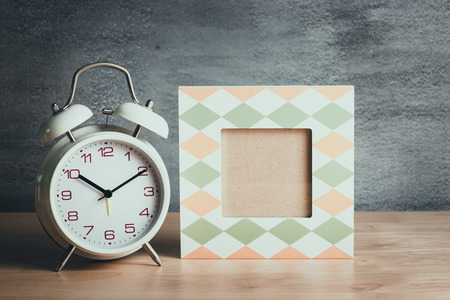 Empty picture frame with white clock on wood tableの写真素材