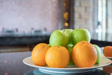 green apples and orange on dishの写真素材