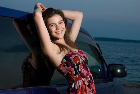 Beautiful girl near the car on sand sea coastの写真素材