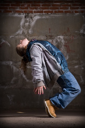 Hip hop girl dancing in modern style over urban grey brick wallの写真素材