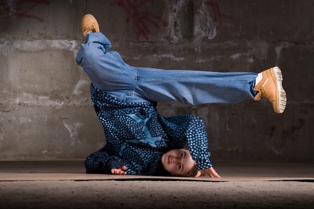 Hip hop girl dancing in modern style over urban grey brick wallの写真素材