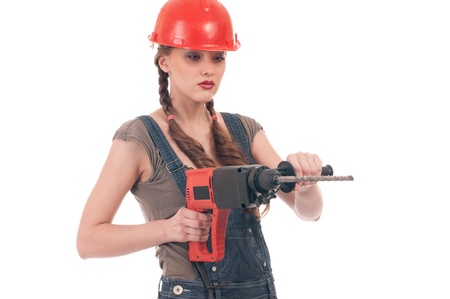 Young playful woman in jeans coverall and orange helmet holding perforator drill with huge augerの写真素材