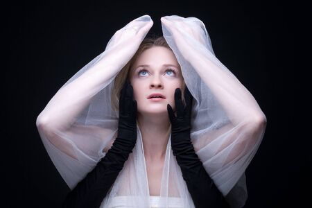 Close up portrait of beautiful blond girl choking by black armsの写真素材