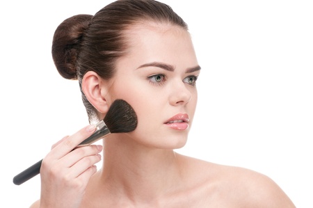 Beautiful young adult woman applying cosmetic paint brush - close-up portrait isolated on whiteの写真素材