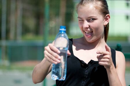 Beautiful young woman drinking water after exercise on sunny summer dayの写真素材
