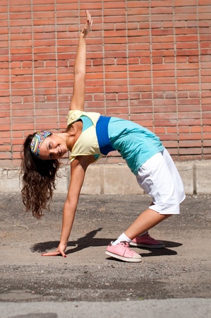 Beautiful teenage girl dancing hip-hop over red brick wallの写真素材