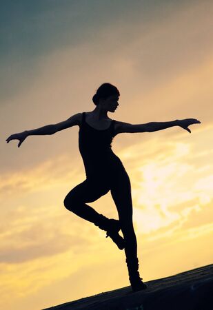 Silhouette photo of dancing woman in modern pilates style over sunset landscape. Yogaの写真素材