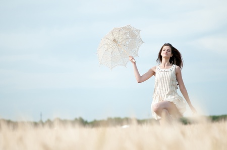 Beautiful sad and lonely woman with umbrella run in wheat field. Timed.の写真素材