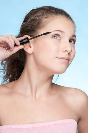 Closeup portrait of young beautiful girl with perfect skin and curly hair. Mascara make up by brush