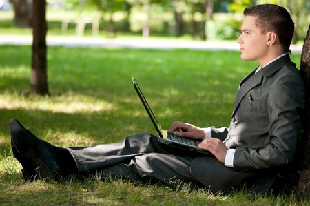 Young business man working on notebook laptop computer, at green park. Student.の写真素材