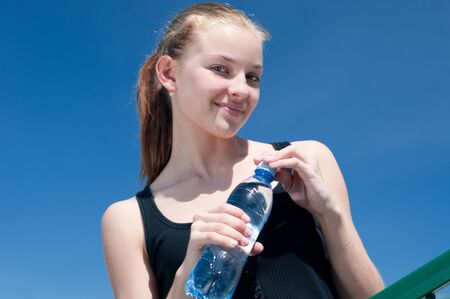 Beautiful young woman drinking water after exercise on sunny summer dayの写真素材