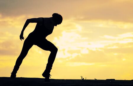 Silhouette of dancing woman in modern pilates style over sunset landscape. Yogaの写真素材