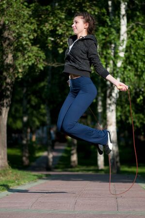 Beautiful young woman doing  exercise with skipping rope at park. Jumpingの写真素材