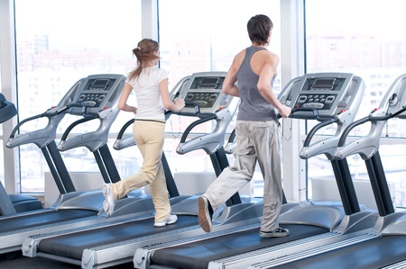 Young woman and man at the gym exercising. Run on on a machine.
