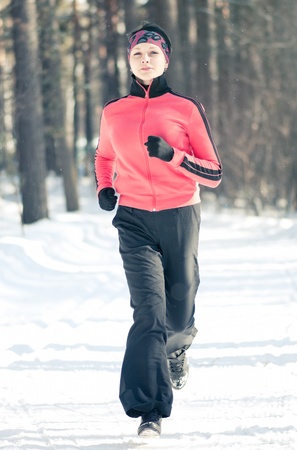 Beautiful young woman running at winter forestの写真素材