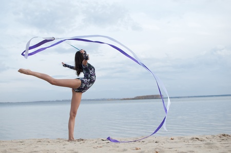 young professional gymnast woman dance with ribbon - outdoor sand beachの写真素材