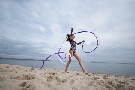 young professional gymnast woman dance with ribbon - outdoor sand beachの写真素材